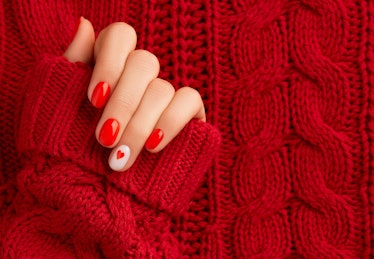 Hand with red nail polish and heart design, the Taylor Swift-themed nail design for fans of her 'Red...