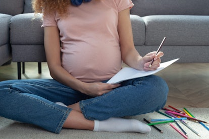 Pregnant woman with baby names list sitting on sofa, closeup