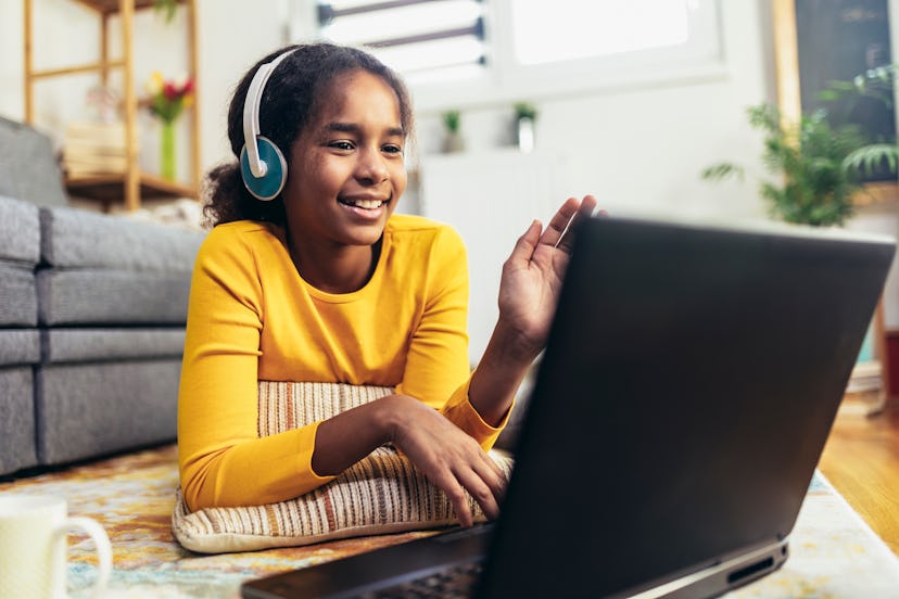 Smiling school African American girl in headphones on her laptop.