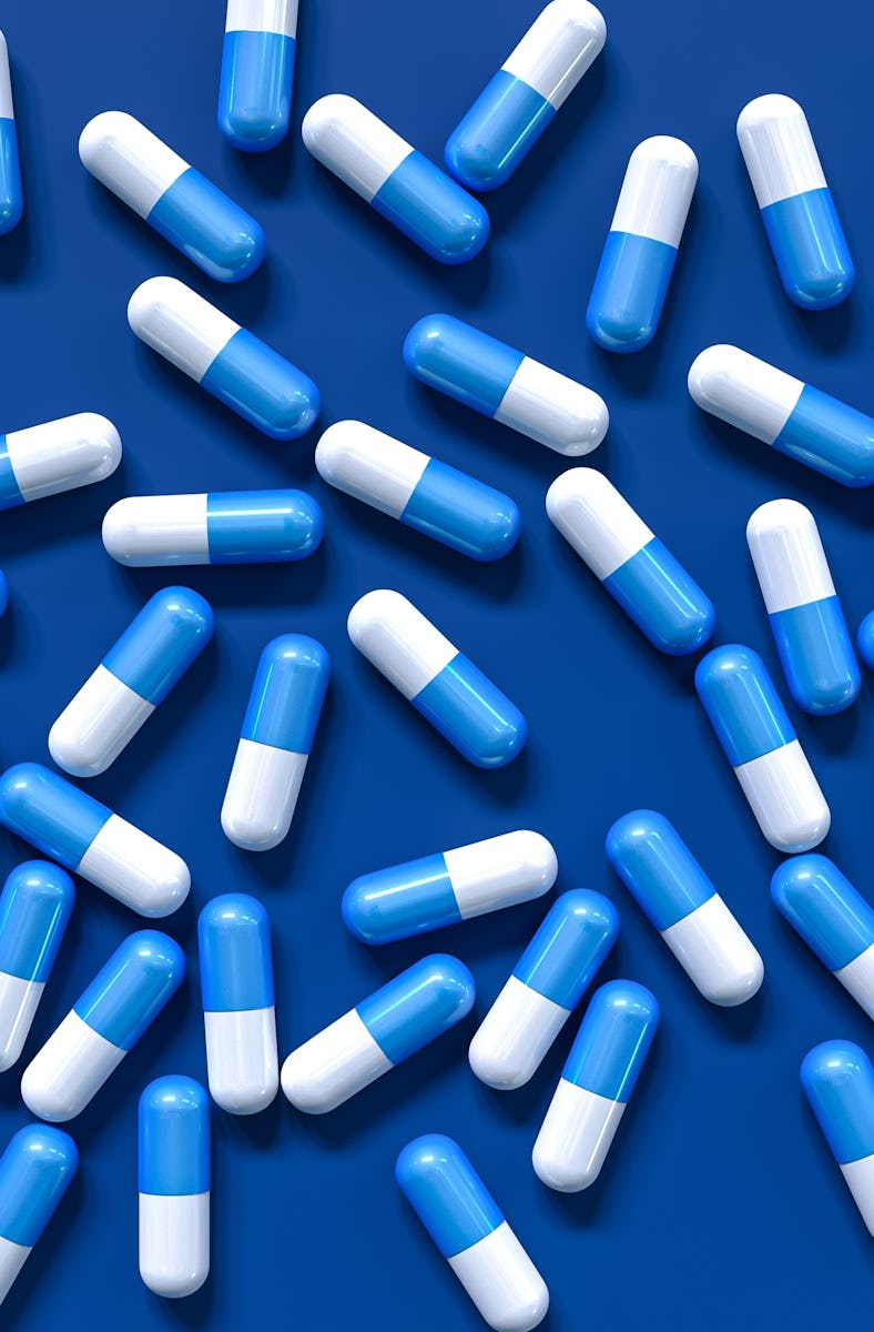 Medical background, two color capsules of probiotics, vitamins, drugs in bulk, top view, blue tones,...