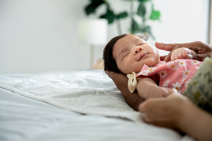 a baby newborn daughter, is 1 months old and is half Thai half Nigerian, sleeping well on the hands ...