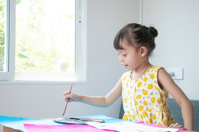 Cute cheerful Asian girl playing with colors.