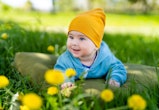 Baby laying in the grass wearing a yellow hat. Adorable baby wearing a sunny yellow hat, peacefully ...