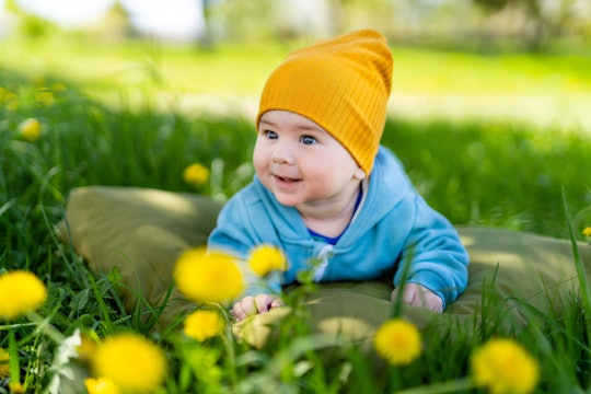 Baby laying in the grass wearing a yellow hat. Adorable baby wearing a sunny yellow hat, peacefully ...