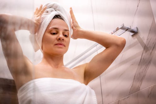 woman wrapping hair in towel after taking a shower