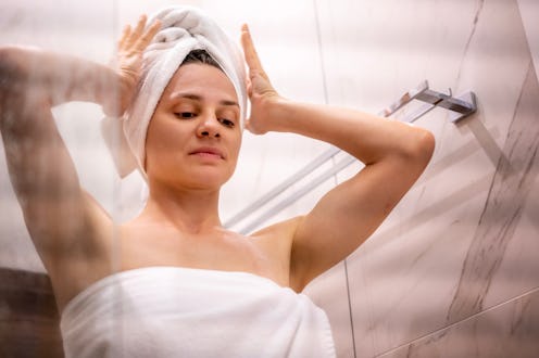 woman wrapping hair in towel after taking a shower