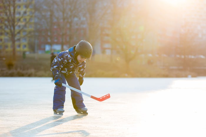 Children, boys, friends and brothers playing hockey and skating in the park on frozen lake, winterti...