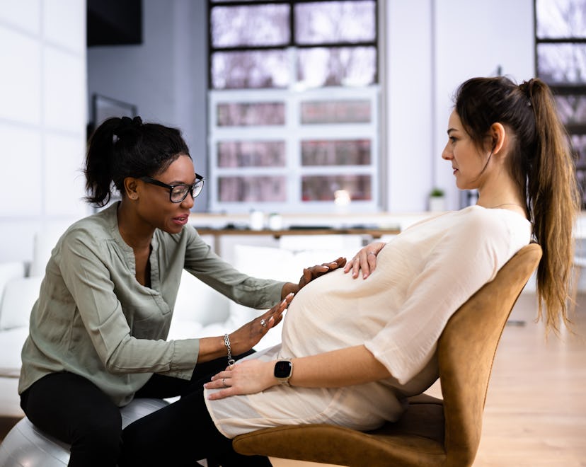Doula touches the stomach of her pregnant patients, in a story about how to choose a doula and doula...
