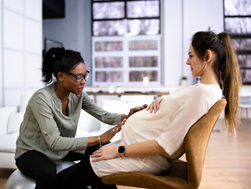 Doula touches the stomach of her pregnant patients, in a story about how to choose a doula and doula...