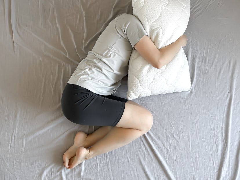 stressed out person in bed hugging pillow; stress might contribute to dementia later in life