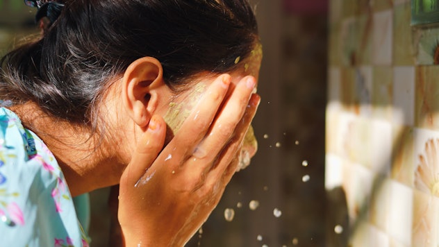 Beautiful woman is washing facial mask in bathroom after applying face mask. 