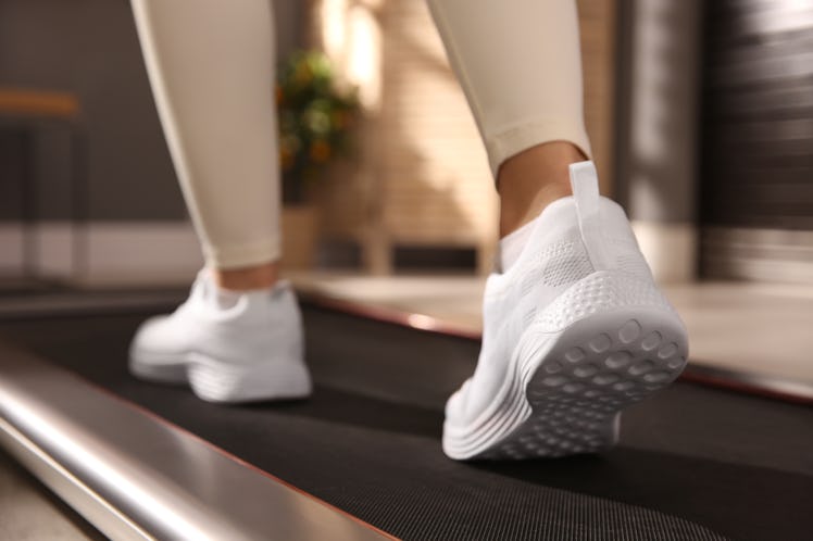 A woman doing cozy cardio on a walking pad at home. 