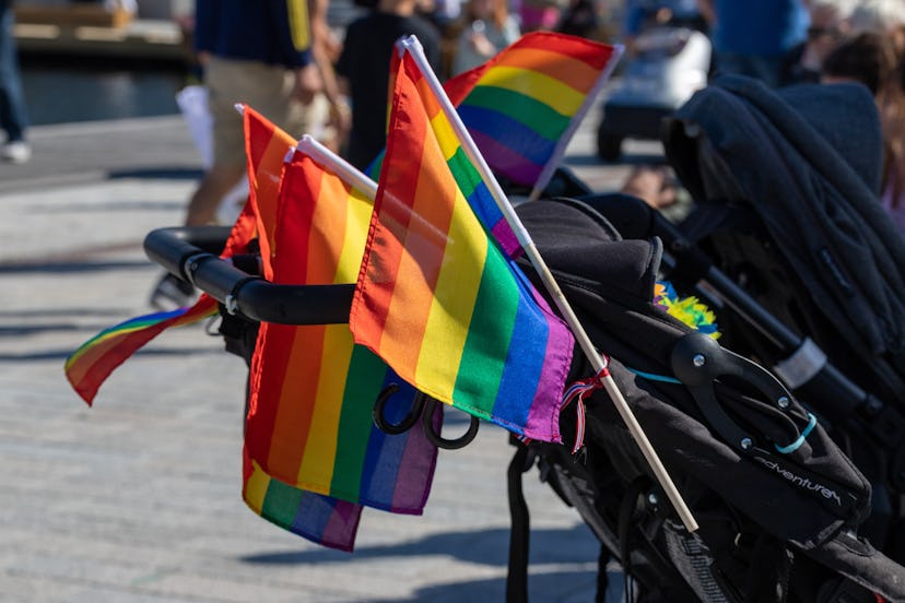 Several rainbow flags on baby strollers for pride celebration.