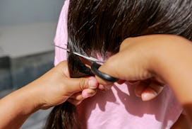 A mother is cutting her daughter's long hair.