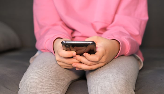 Close-up of children's hands holding, using smartphone. Child plays online games. Internet addiction...