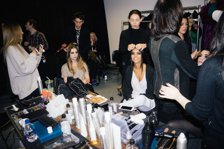 Hairdressers preparing hairstyles for female models before a runway walk