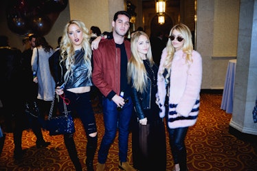 A man and three blonde women posing for a photo at a fashion week event