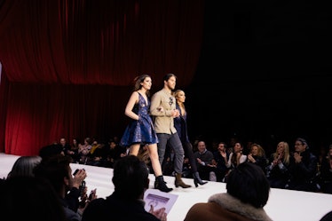 Andrew Warren walking a runway with two female models