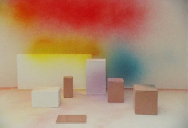 Differently shaped boxes in front of a red, yellow, blue, and white wall 