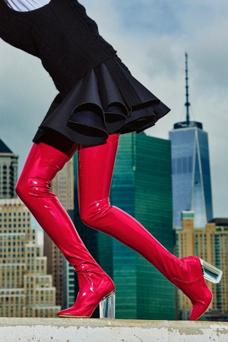 A woman walking while wearing a black skirt, red leggings, and red heel boots 