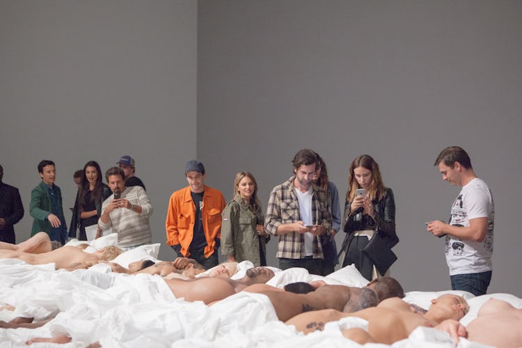 A group of people looking at Kanye West's Famous sculpture