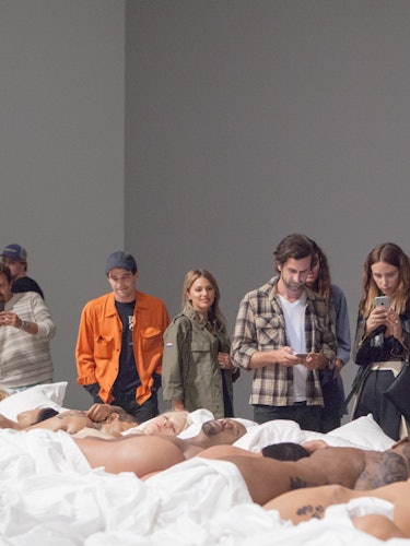 A group of people looking at Kanye West's Famous sculpture
