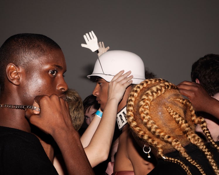A model getting his hat with hands on it, put on his head backstage at VFiles' Spring 2017 show 