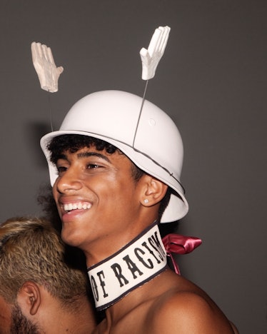 A model backstage at VFiles wearing a hat with plastic hands attached to it 
