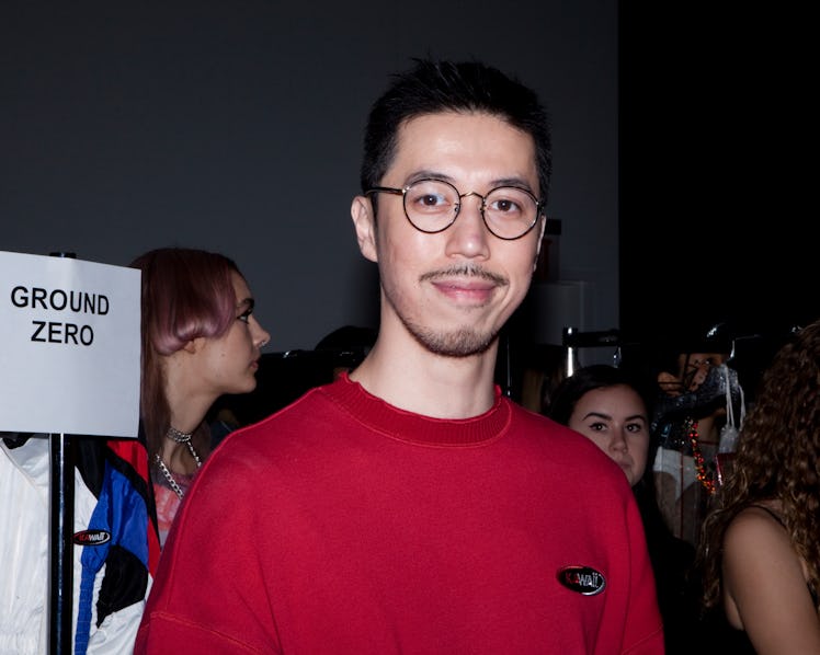 A man backstage at the VFiles Spring 2017 show in a red sweater and round glasses 