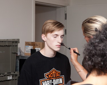 A makeup artist touching up a male model's makeup backstage at the VFiles Spring 2017 show 