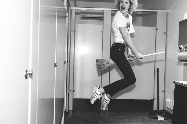 A model posing with a broom in a bathroom backstage at Alexander Wang Spring 2017