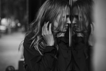 Uma Thurman looking herself in the mirror while wearing a black blouse