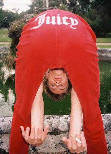 A model bending over showing "Juicy" written on the backside of his Juicy Couture sweatpants 