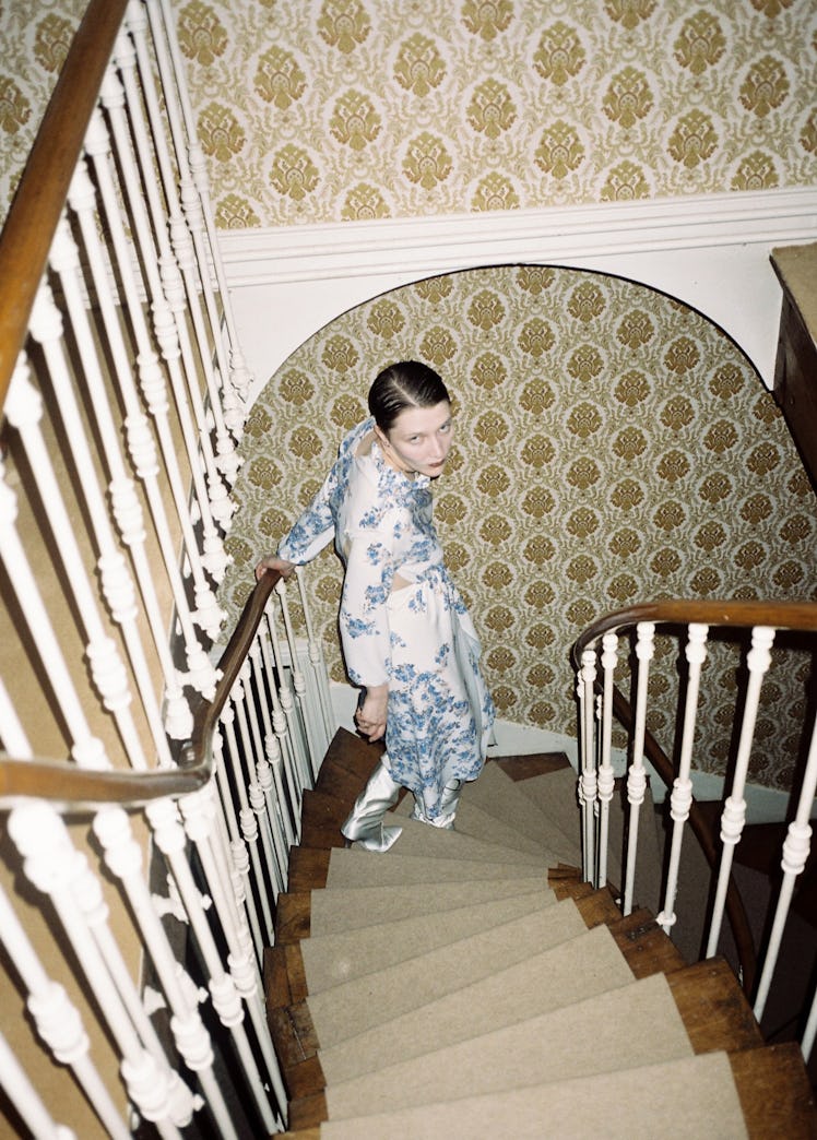 A model walking down a spiral staircase in a white and blue dress 