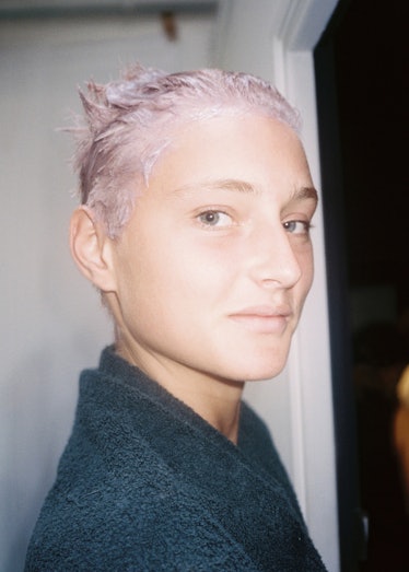 A model with bleach drying on their hair, looking at the camera