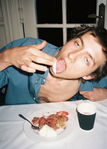 A model eating with his fingers in a blue shirt 