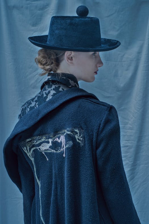 A model wearing a hat and coat by a Chinese fashion designer Deepmoss