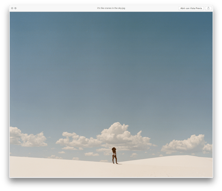 Solange posing in a white bodysuit with the blue sky in background