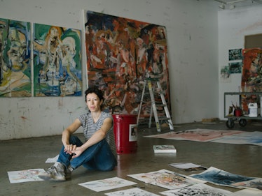 Cecily Brown sitting on the floor in her art in her New York studio