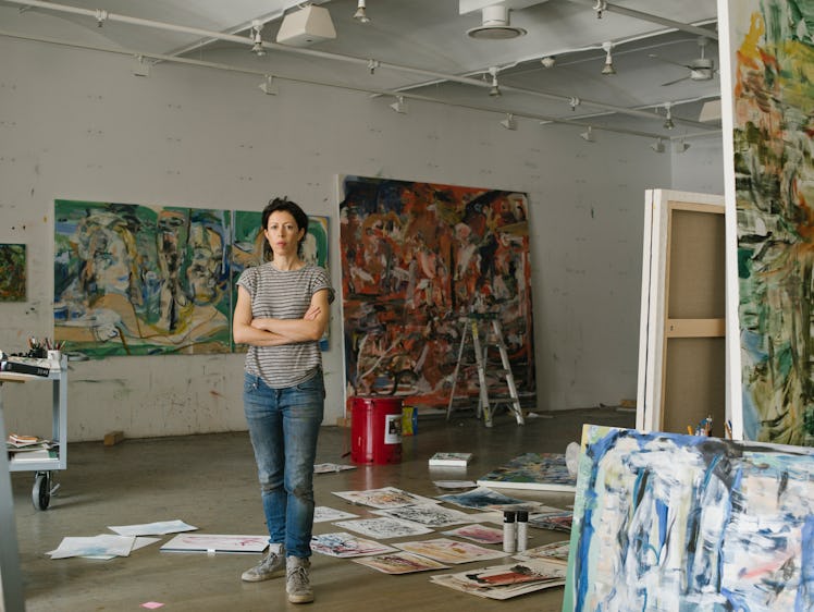 Cecily Brown standing and looking at her art in her New York studio