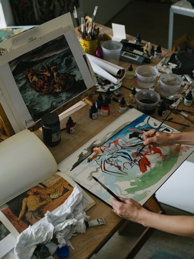 Cecily Brown holding one of her paintings and working on it in her New York studio