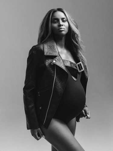 Pregnant Ciara posing while wearing a black bodysuit topped with an oversized black leather jacket