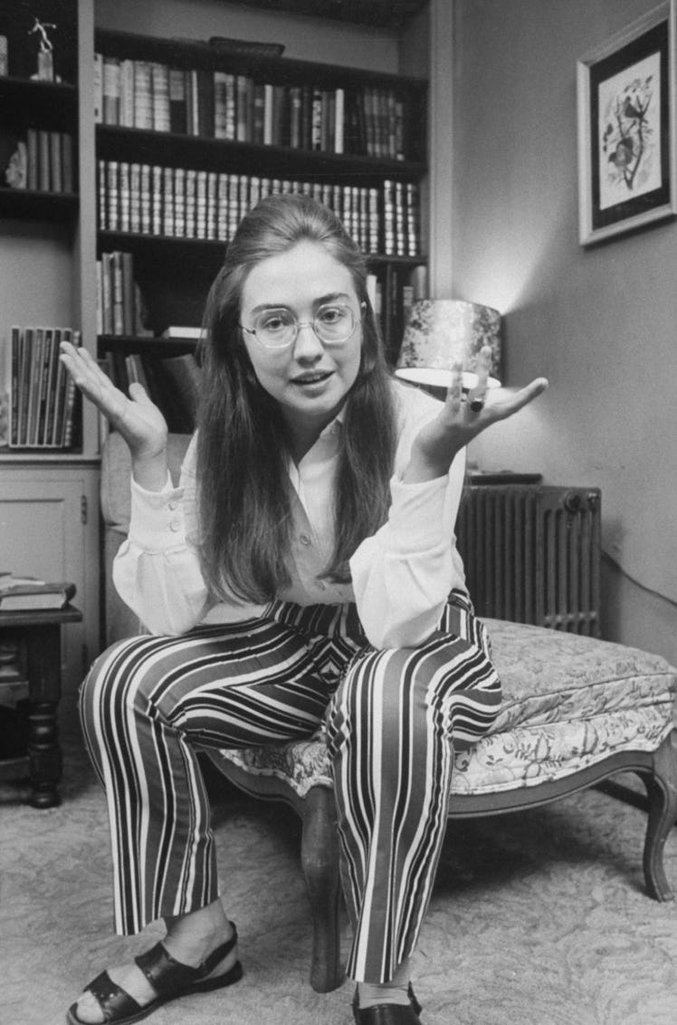 Young Hillary Clinton in a white shirt and striped pants while wearing glasses