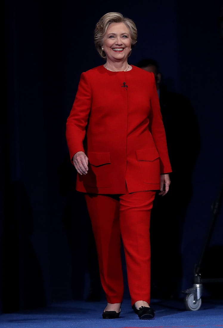 Hillary Clinton walking and smiling in a red suit in October 2016