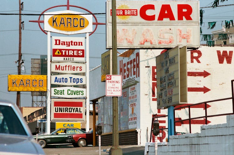 Signs for the car wash and car repair, and a sign for no parking on the lighting pole on the street