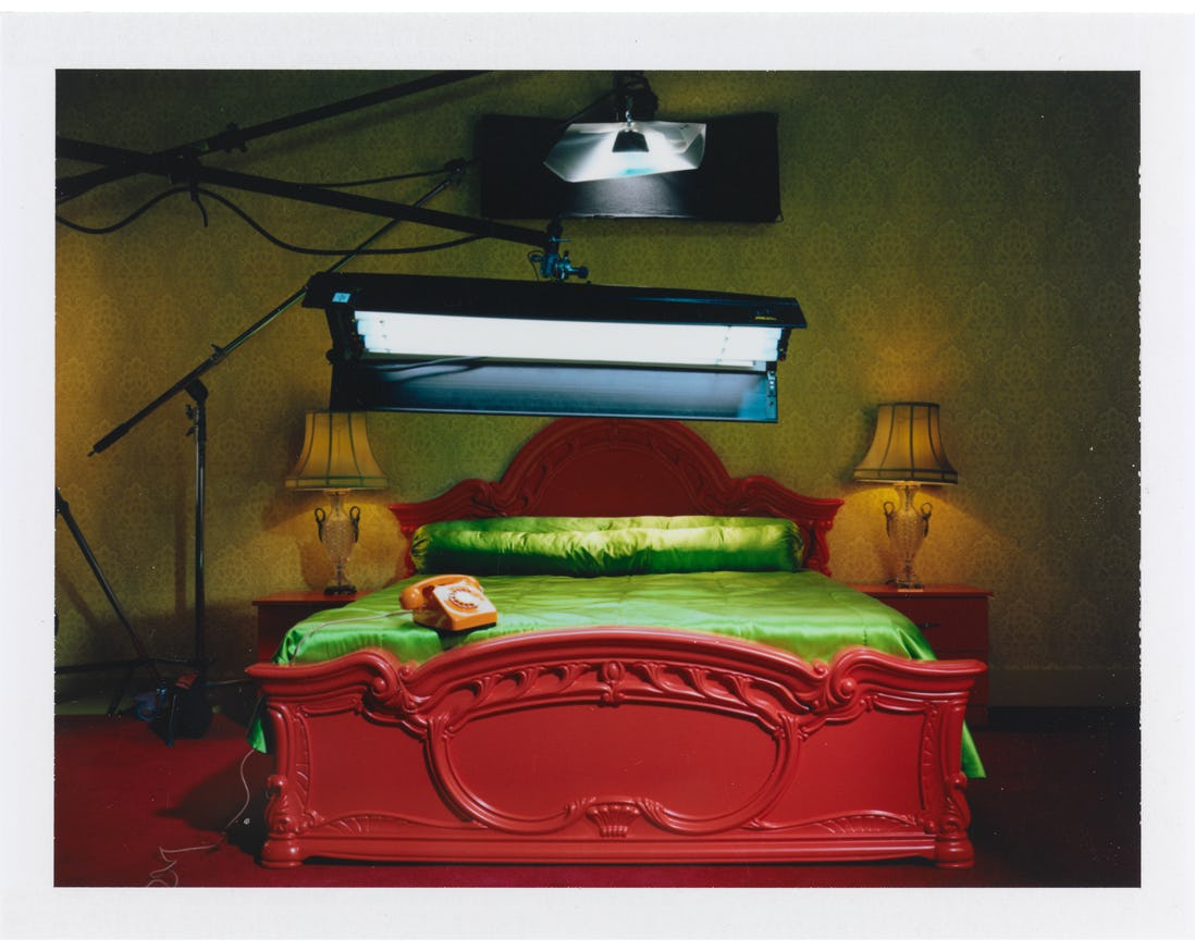 Miles Aldridge's polaroid featuring a spotlight above a red bed with green sheets