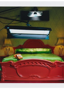 Miles Aldridge's polaroid featuring a spotlight above a red bed with green sheets