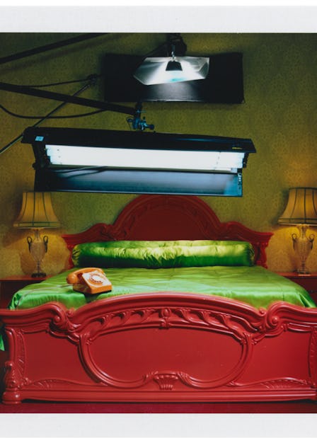 Miles Aldridge's polaroid featuring a spotlight above a red bed with green sheets