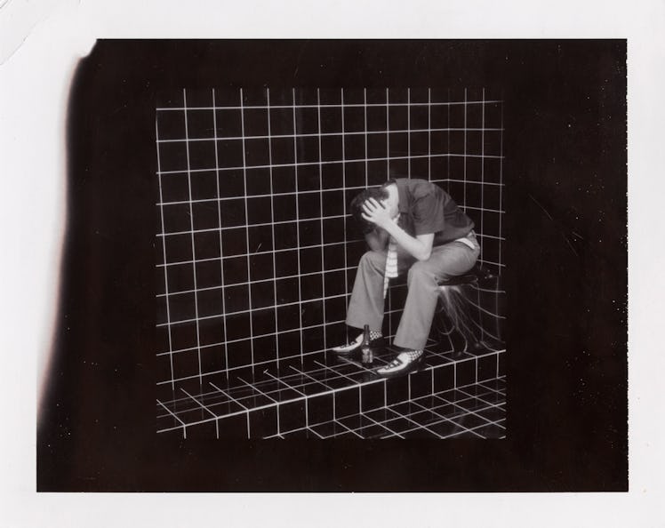 Miles Aldridge's polaroid featuring a man sitting in a corner of a room with tiles in black and whit...