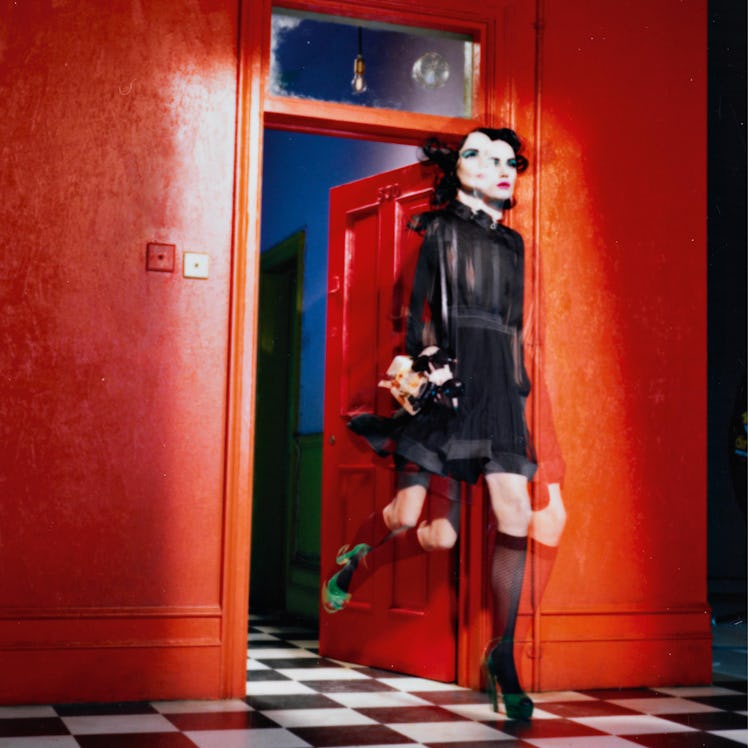 Miles Aldridge's polaroid featuring a blurred woman in a black dress entering a room with a red wall
